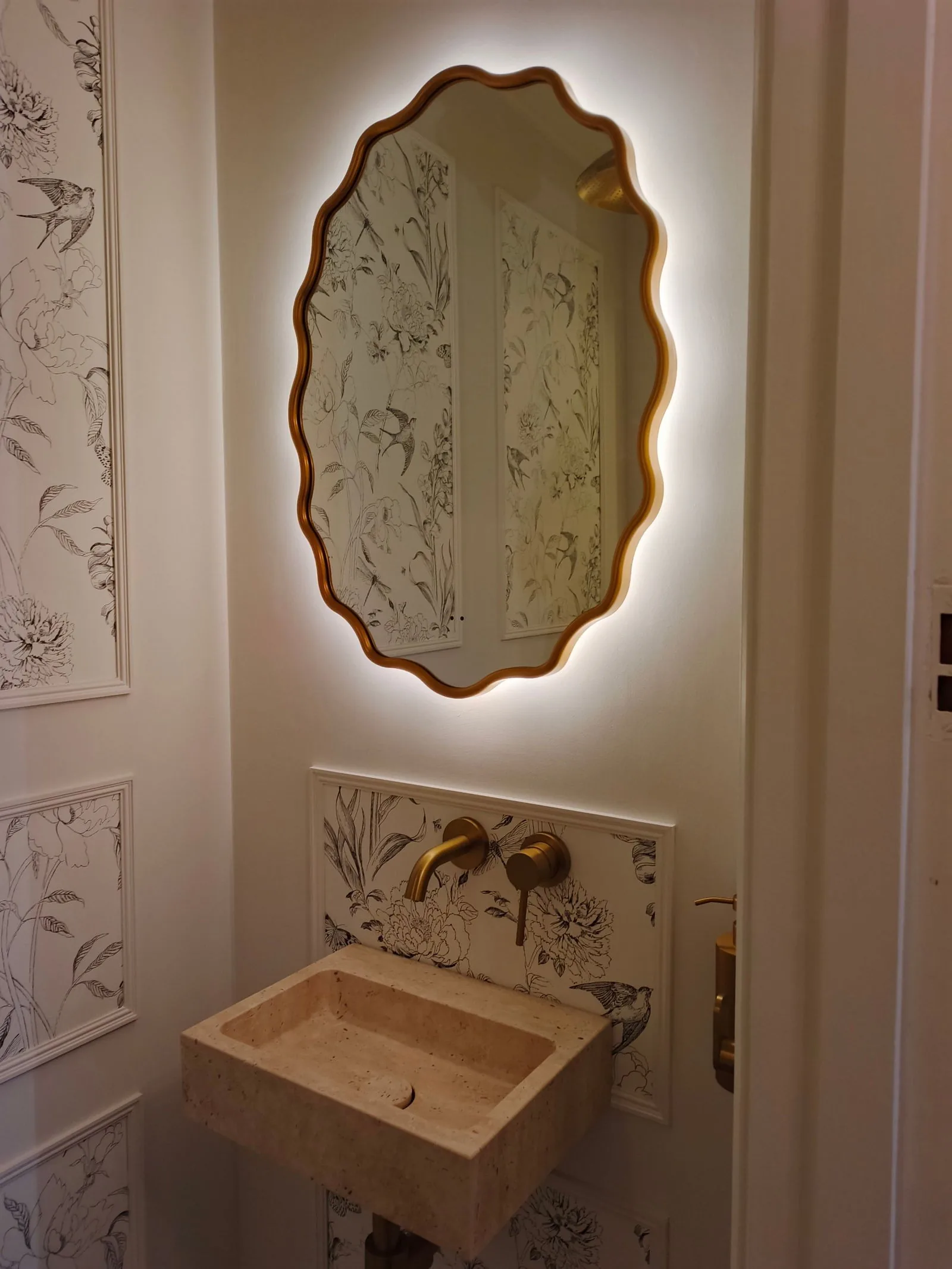 Backlit scalloped mirror on a permanent feed above a stone basin in a Poole BH14 cloakroom