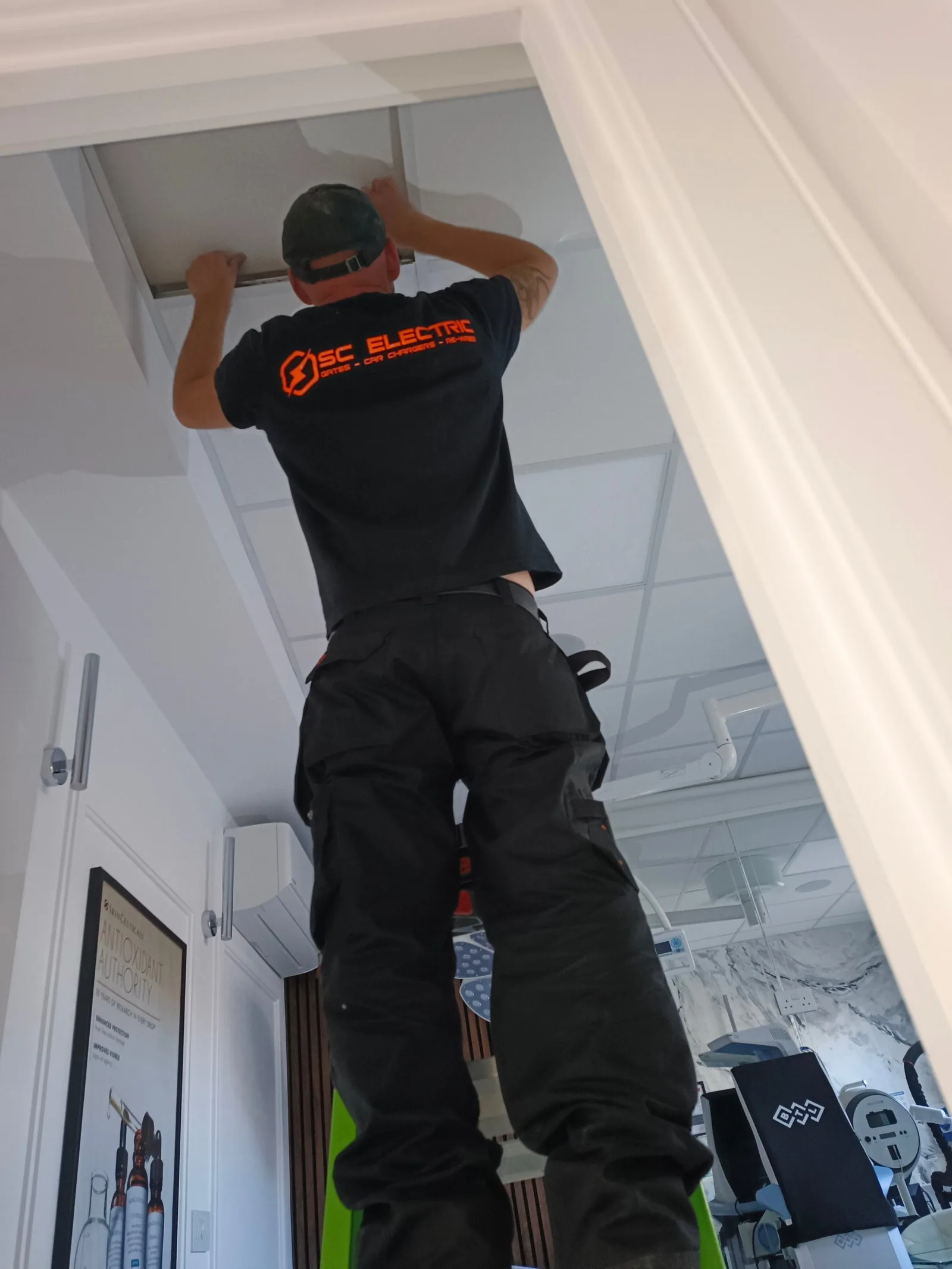 SC Electric electrician working above the suspended ceiling at a clinic in Poole BH14
