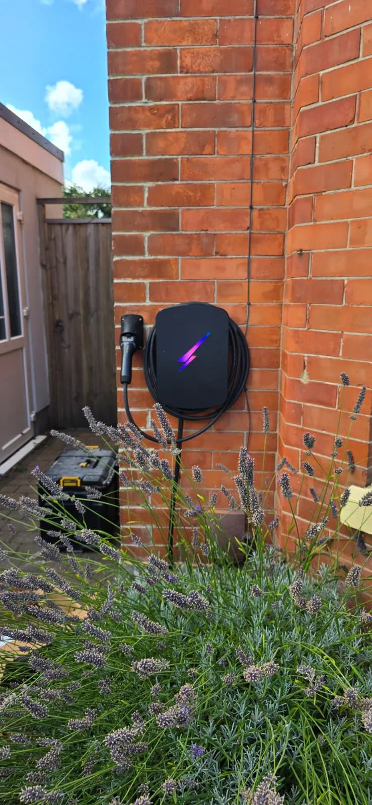 Wider view of an EV charger, cable storage and plug holder on a brick wall in Southbourne