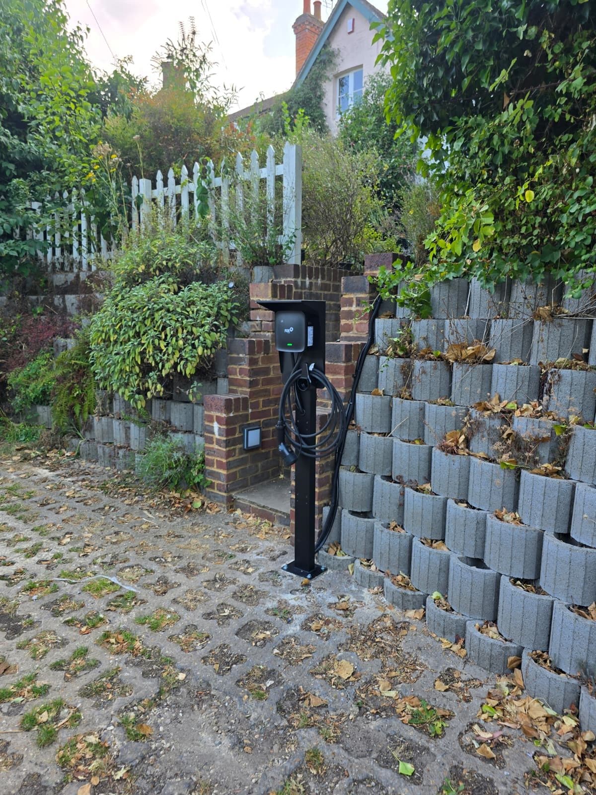 A clean frontal view of the pedestal mounting canopy with coiled charging lead.
