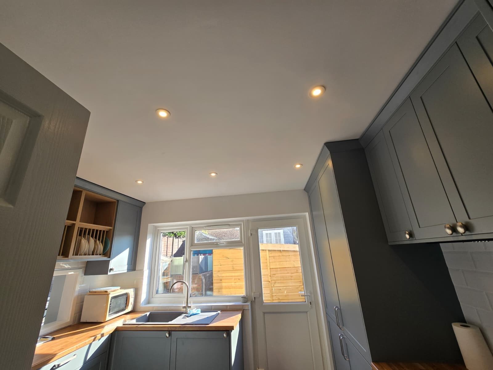 Marking out and cutting ceiling downlight positions set forward of future wall units.